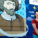 Ana Langeheldt junto a uno de sus murales, cartelista de las Fiestas de la Primavera de Sevilla 2027
